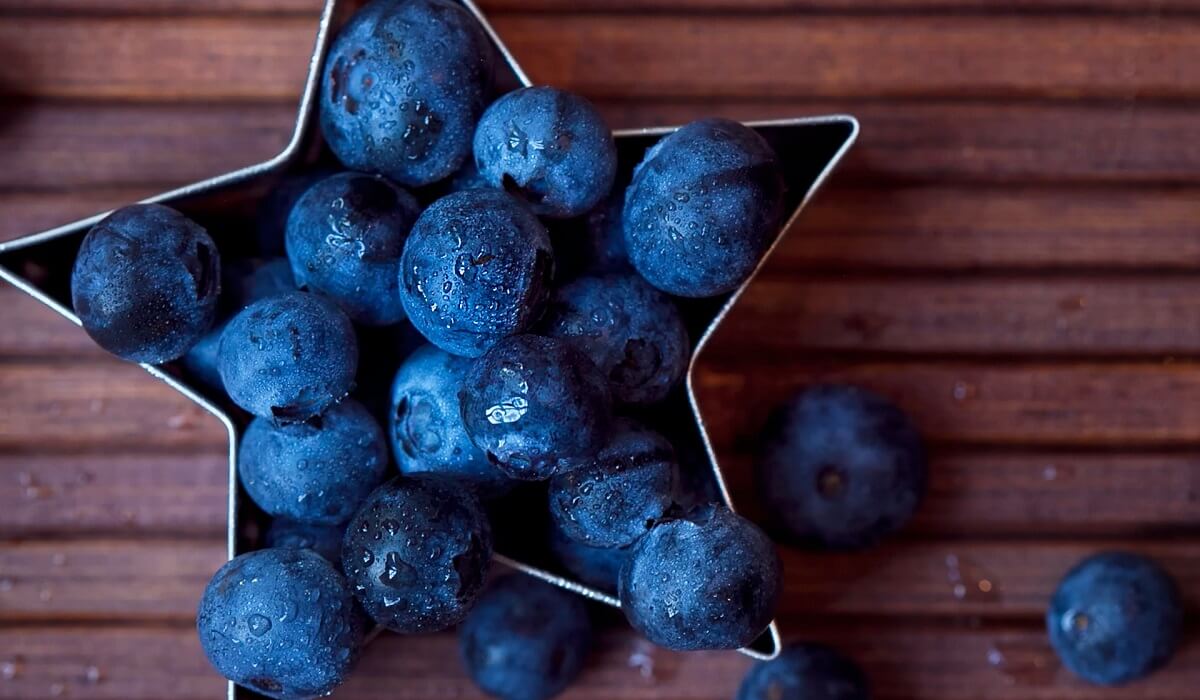 Blueberries on wooden surface and in star-shaped bowl