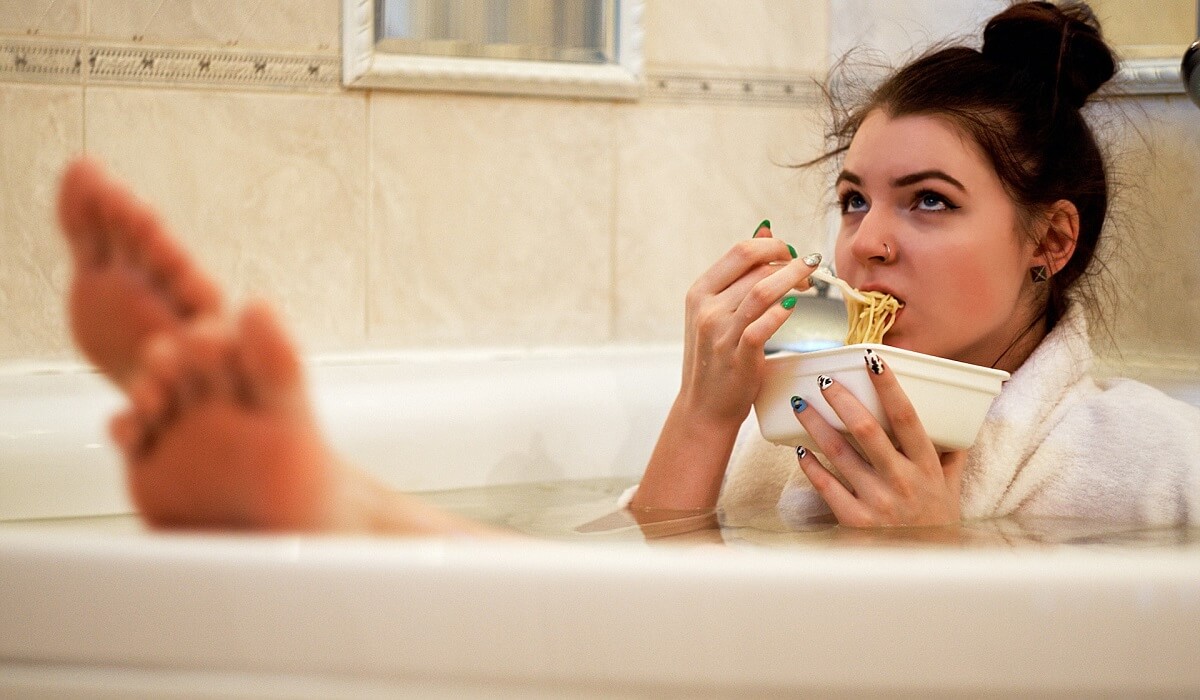 Girl in bathtub holding white ceramic mug