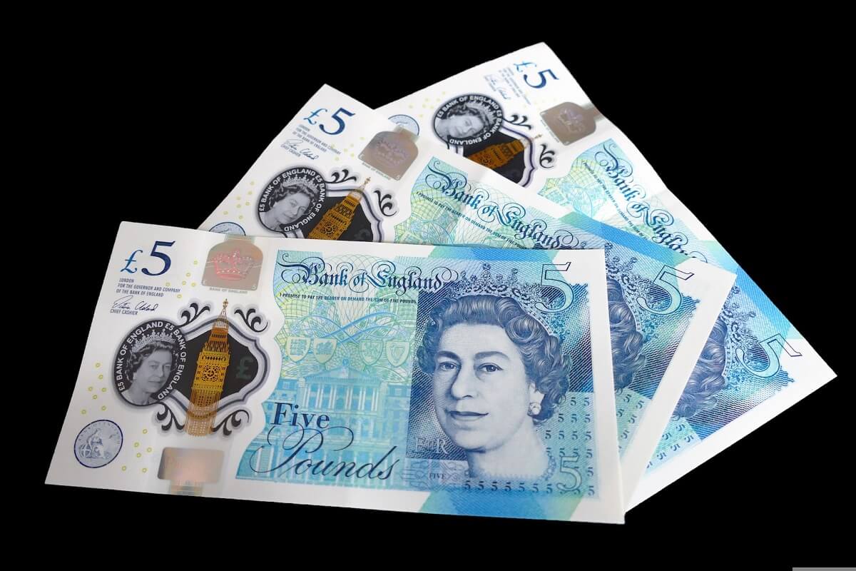 Three British £5 banknotes on a black background