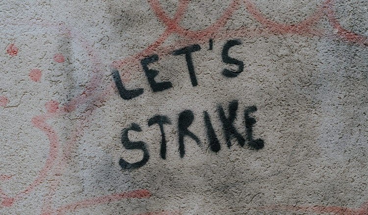 The inscription "Let's strike" on a gray wall
